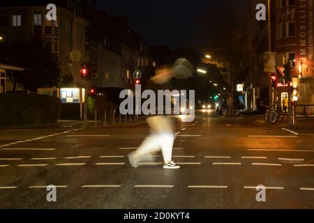 Köln, NRW, Deutschland 10 02 2020, Nachtszene an einer Kreuzung in Köln überquert ein Mann den pedastrischen Weg, Bewegungsunschärfe Stockfoto