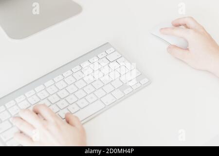 Nahaufnahme der Hände von Frauen mit einer kabellosen Maus und Computertastatur Stockfoto