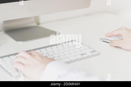 Nahaufnahme der Hände von Frauen mit einer kabellosen Maus und Computertastatur Stockfoto