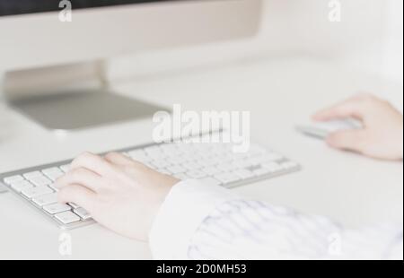 Nahaufnahme der Hände von Frauen mit einer kabellosen Maus und Computertastatur Stockfoto