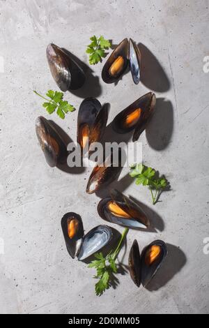 Gekochte Muscheln mit Gewürzen auf grauem Steingrund, vertikale Ausrichtung Stockfoto