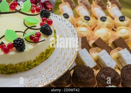 Gebäck: Soufflekuchen mit Johannisbeeren, Brombeeren und Pistazien auf dem Hintergrund von Mini-Desserts Stockfoto