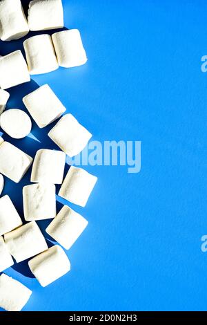 Marshmallows auf blauem Hintergrund mit Kopierbereich. Flach liegend. Draufsicht. Hintergrund oder Textur von bunten Mini Marshmallows. Winter Food Hintergrund Stockfoto