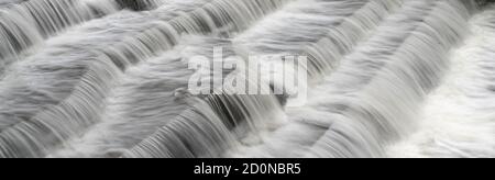 Blick auf Wasser bei langer Exposition, um glatt verschwommen zu werden Wassereffekte weiße Wasserwellen über dem Fluss Wehr Stockfoto