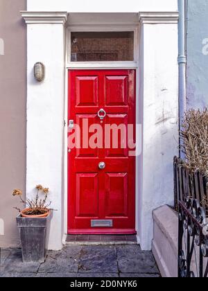 Rot-Weißer Punsch. Eine rötliche Tür, die von einem überwältigenden weißen Rahmen umgeben ist, spricht von einem starken Charakter, der darin versteckt ist. Notting Hill, London. Stockfoto