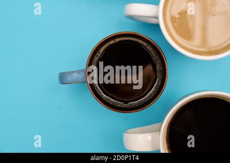 Draufsicht auf verschiedene Arten von heißem Kaffee - schwarz und mit Milch auf pastellblauem Hintergrund. Stockfoto