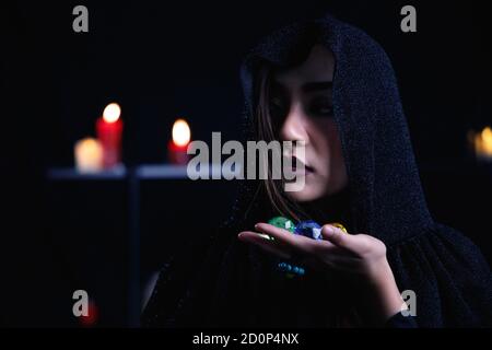 Mystery Frau in schwarzer Kapuze halten bunte Juwel auf dunklem Hintergrund. Stockfoto