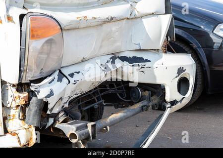Nahaufnahme des Unfallwagens. Die Vorderseite des Fahrzeugs ist hellgrau, stark beschädigt und versehentlich auf der Straße zerschlagen. Versicherungsfall. Stockfoto