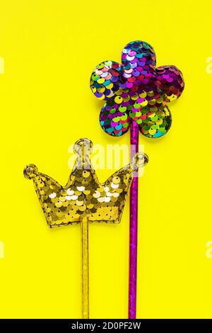 Goldene Krone und rosa Blume aus runden Pailletten auf gelbem Hintergrund. Mode Party Accessoires mit Kopierer Platz. Festliche, flache Laie. Minimalistischer Stil. Stockfoto