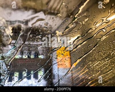 Blick von innen auf Windschutzscheibe mit Wassertropfen und Streifen In automatischer Waschanlage Stockfoto