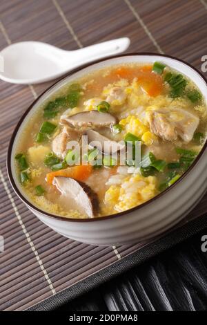 Zosui ist eine beruhigende japanische Reissuppe, die in einer herzhaften Dashi-Brühe mit Gemüse, Eiern, Pilzen und Hühnchen aus nächster Nähe in einer Schüssel auf dem Tisch zubereitet wird. Stockfoto