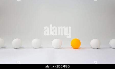 Anderes Konzept Foto. Eine orangefarbene Kugel richtet sich mit einer weißen Kugel mit hellem Hintergrund aus Stockfoto
