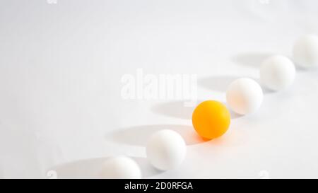 Anderes Konzept Foto. Eine orangefarbene Kugel richtet sich mit einer weißen Kugel mit hellem Hintergrund aus Stockfoto