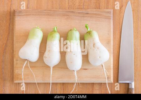 Homegrown mooli Rettich (Daikon) Wurzeln auf einem Schneidebrett und Küchentisch in Großbritannien. Flach legen Lebensmittel Zutaten Stockfoto