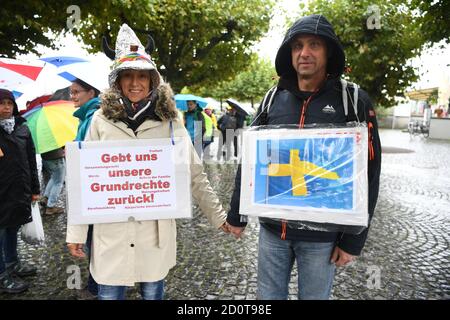 Konstanz, Deutschland. 03.Okt, 2020. Paarweise verläuft am Ufer des Bodensees entlang. Während er auf einem Plakat die schwedische Flagge zeigt, heißt es auf dem Plakat: "Gib uns unsere Grundrechte zurück." Am Nachmittag wollen sich viele Menschen rund um den Bodensee zu einer sogenannten Friedens-Menschenkette zusammenschließen, die durch Deutschland, Österreich, Liechtenstein und die Schweiz führen wird. Quelle: Felix Kästle/dpa/Alamy Live News Stockfoto