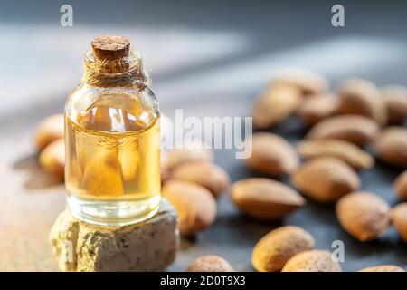 Glasflasche mit Mandelöl und Mandeln auf dunklem Hintergrund. Stockfoto