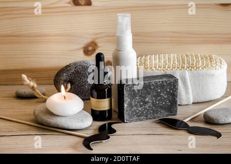 Oben sehen Satz von verschiedenen Mann Spa-Produkte Dinge. Naturholzscheibe Hintergrund mit flachen Meeressteinen. Graues Tonseifenstück, Bartöl, feuchtigkeitsspendend. Stockfoto
