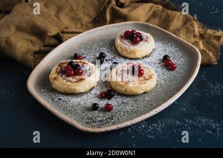 Hüttenkäse-Pfannkuchen mit Waldbeeren und Puderzucker Stockfoto