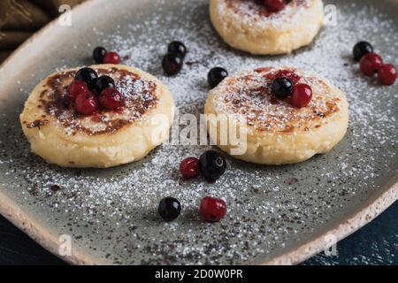 Hüttenkäse-Pfannkuchen mit Waldbeeren und Puderzucker Stockfoto