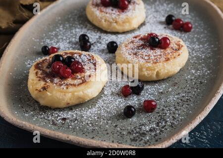 Hüttenkäse-Pfannkuchen mit Waldbeeren und Puderzucker Stockfoto