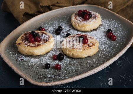 Hüttenkäse-Pfannkuchen mit Waldbeeren und Puderzucker Stockfoto