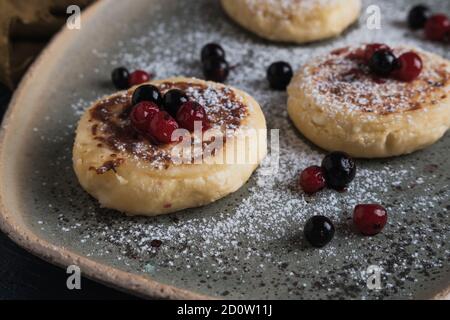 Hüttenkäse-Pfannkuchen mit Waldbeeren und Puderzucker Stockfoto