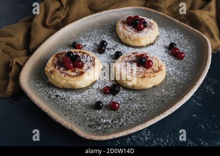 Hüttenkäse-Pfannkuchen mit Waldbeeren und Puderzucker Stockfoto