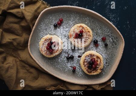 Hüttenkäse-Pfannkuchen mit Waldbeeren und Puderzucker Stockfoto