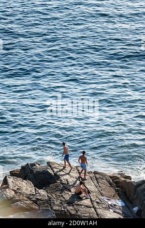 PORTONOVO, SPANIEN - 14. AUGUST 2020: Drei junge Fischer fischen an einem ruhigen klaren Abend in den Rias Baixas in Galicien, Spanien. Stockfoto