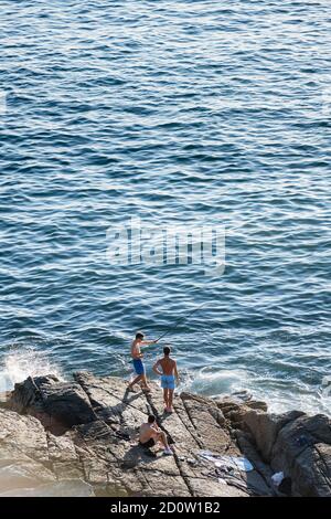 PORTONOVO, SPANIEN - 14. AUGUST 2020: Drei junge Fischer fischen an einem ruhigen klaren Abend in den Rias Baixas in Galicien, Spanien. Stockfoto