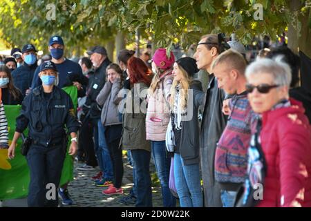 Konstanz, Deutschland. Oktober 2020. Die Menschen bilden eine sogenannte Friedens-Menschenkette, die durch Deutschland, Österreich, Liechtenstein und die Schweiz rund um den Bodensee führen soll, während links Anhänger der Corona-Maßnahmen daran vorbeilaufen. Quelle: Felix Kästle/dpa/Alamy Live News Stockfoto