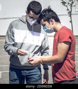 Zwei junge Menschen teilen sich hydroalkoholisches Gel, um sich während der Desinfektion zu desinfizieren Die Zeit der sozialen Distanz, um sich vor dem covid19 zu schützen Stockfoto