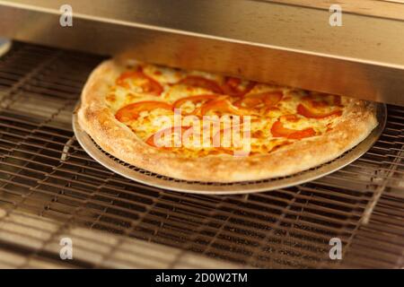 Frisch gebackene Pizza kommt aus dem modernen Ofen in einem Restaurant Stockfoto