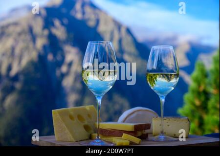Schmackhafter Käse und Wein aus Savoyen in Frankreich, beaufort, abondance, emmental, Tomme und Reblochon de savoie Käse und ein Glas Weißwein serviert Stockfoto