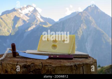 Käsesammlung, französischer emmental de savoie Käse mit runden Löchern, serviert im Freien in der Savoyer Region, mit Berggipfeln im Sommer auf dem Backgrou Stockfoto