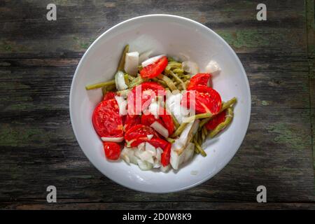 Grüne Bohnen in Salat mit Tomaten und Zwiebeln auf verfallenen Holztisch Schreibtisch Stockfoto