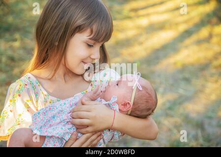 Die ältere Schwester hält das Neugeborene in ihren Armen. Selektiver Fokus. Menschen. Stockfoto