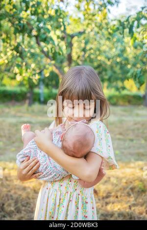 Die ältere Schwester hält das Neugeborene in ihren Armen. Selektiver Fokus. Menschen. Stockfoto