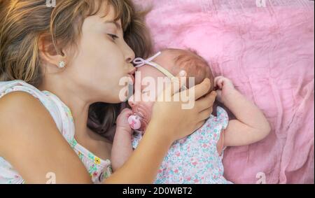 Die ältere Schwester hält das Neugeborene in ihren Armen. Selektiver Fokus. Menschen. Stockfoto