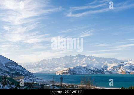 Charvak Bergsee in Usbekistan an einem verschneiten frostigen Tag, umgeben von den Tien Shan Bergen Stockfoto