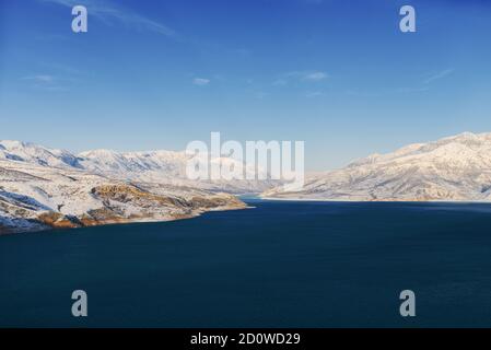 Erstaunliche Winterlandschaft des Charvak Stausees mit blauem gesättigtem Wasser In Usbekistan an einem Wintertag Stockfoto