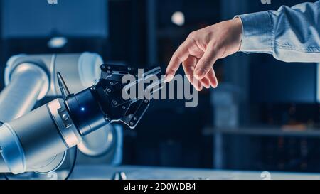 Futuristischer Roboterarm berührt menschliche Hand in der Menschheit und Künstliche Intelligenz verbindende Geste. Bewusste Technik Trifft Auf Menschlichkeit. Konzept Stockfoto