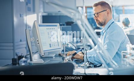 Elektronikentwickler, der am Computer arbeitet, Motherboard entwickelt, Geräte instandsetzt und Leiterplatten löt. Professionell Stockfoto