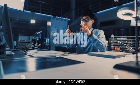 Professioneller japanischer Entwicklungsingenieur in blauem Hemd, der ein Foto nimmt Der technischen Zeichnungen auf seinem Smartpgone in der High Tech Forschungslabor Stockfoto