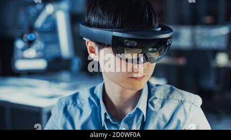 Professionelle japanische Elektronik-Entwicklungsingenieur in Blau Shirt trägt Ein Virtual Reality-Headset und ein Blick auf die High-Tech Forschung Stockfoto