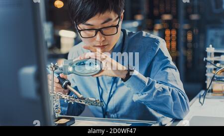 Nahaufnahme eines professionellen japanischen Elektronikingenieurs in Blaues Hemd Löten einer Leiterplatte in einem High Tech Forschungslabor mit Stockfoto