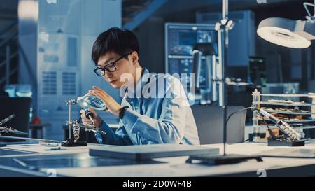 Professioneller japanischer Elektronikentwickler in blauem Hemd ist Löten Eine Leiterplatte in einem High-Tech-Forschungslabor mit Modern Stockfoto