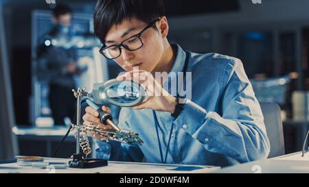 Professioneller japanischer Elektronikentwickler in blauem Hemd ist Löten Eine Leiterplatte in einem High-Tech-Forschungslabor mit Modern Stockfoto