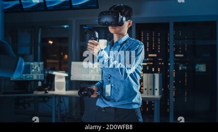 Professioneller japanischer Entwicklungsingenieur in blauem Hemd verwendet Augmented Reality-Headset und Joysticks in einem High-Tech-Forschungslabor Mit Stockfoto