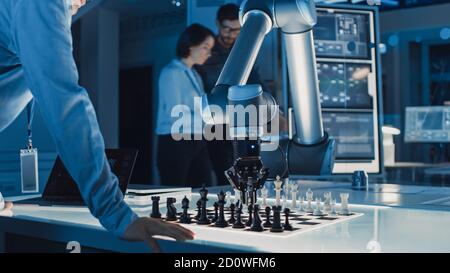Professioneller japanischer Entwicklungsingenieur testet eine künstliche Intelligenz-Schnittstelle, indem er Schach mit einem futuristischen Roboterarm spielt. Sie sind in Stockfoto